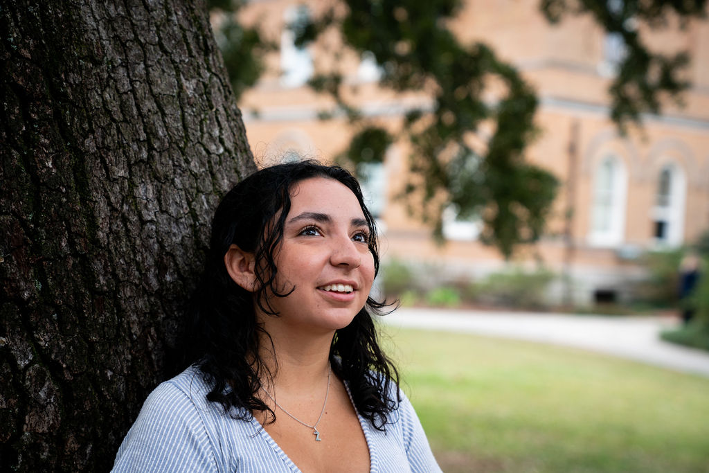 woman leaning on a tree smiling